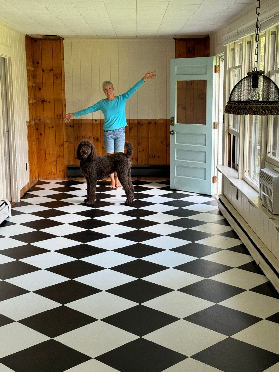 Vinyl Composition Tile (VCT) | woman and a large poodle in a room with bold, black and white checkered VCT flooring