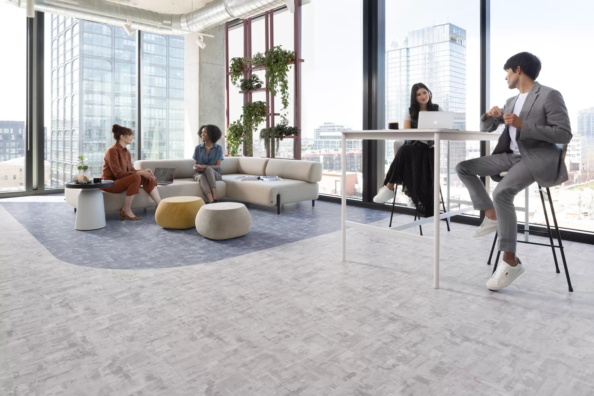 Tarkett Flooring two pairs of people sitting in open collaboration area in office with couch seating and high top table